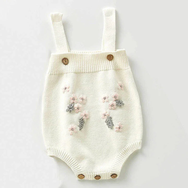 White knitted baby romper with floral embroidery, button straps, and bottom buttons