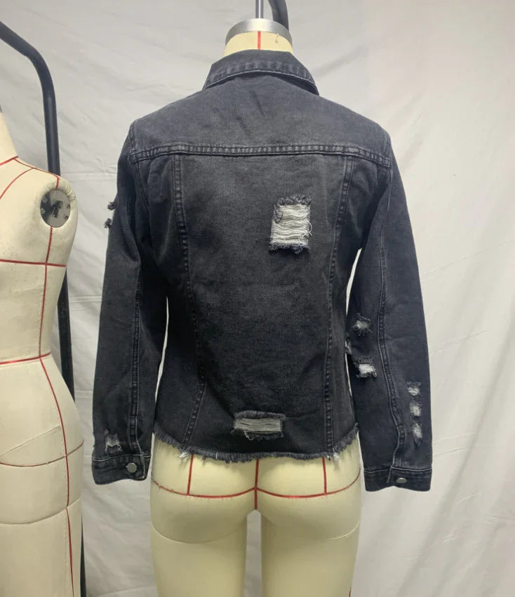Back view of black distressed denim jacket on mannequin with ripped details on sleeves and back