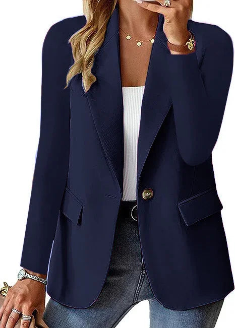 Woman wearing navy blue tailored blazer with single button, paired with white top and jeans