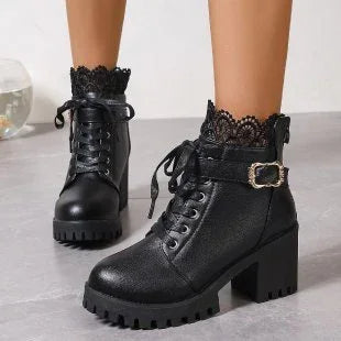 Black chunky heeled ankle boots with lace trim and buckle detail on gray floor