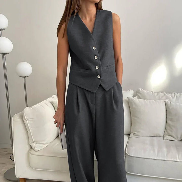 Woman wearing dark gray sleeveless buttoned vest and matching wide-leg pants indoors