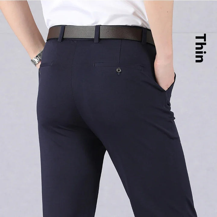 Back view of man wearing slim fit navy blue dress pants with black belt and white shirt