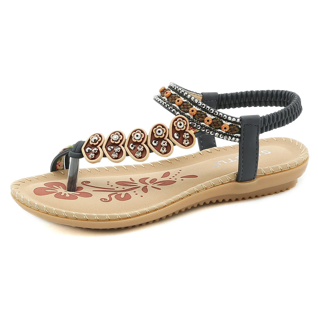 Brown and black flat women's sandal with decorative heart-shaped beads and floral footbed pattern
