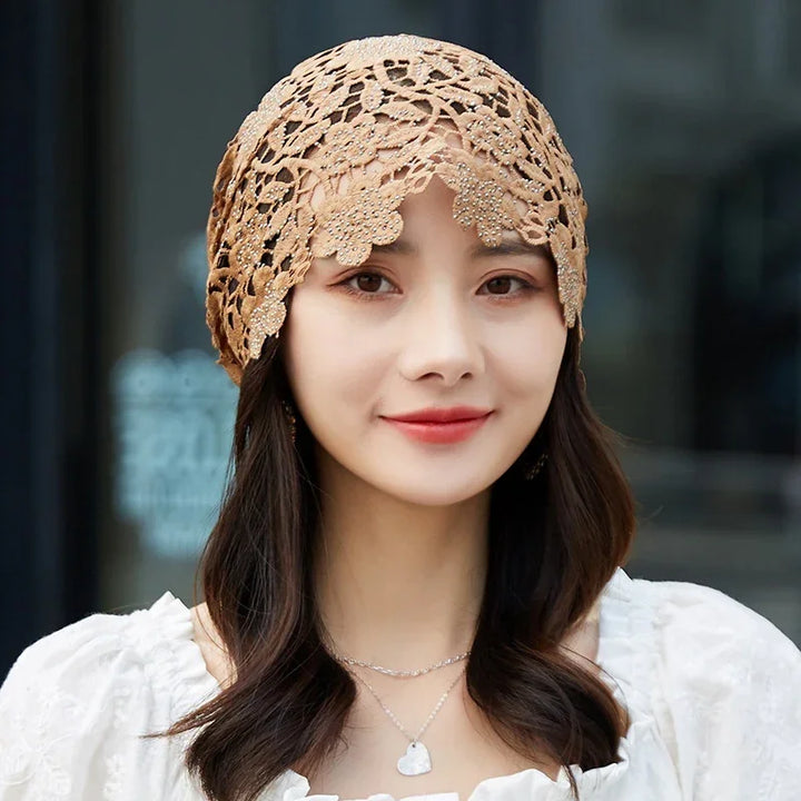 Woman with long dark hair wearing beige crochet beanie and white blouse, smiling outdoors