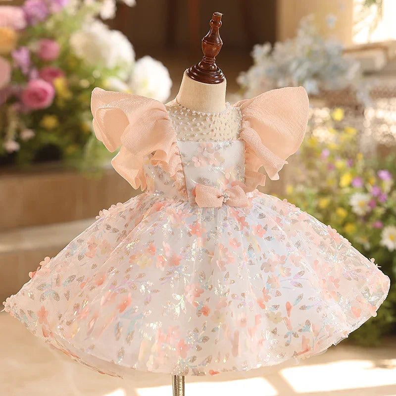 Elegant baby girl dress with puff sleeves, floral patterns, pearl neckline, and bow detail on mannequin