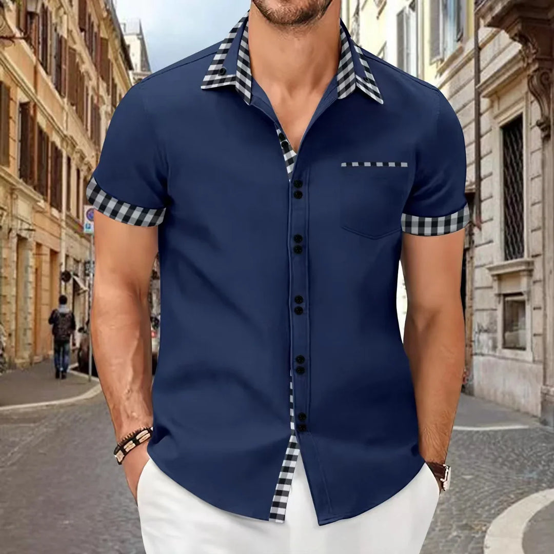 Man wearing navy blue short-sleeve shirt with black-and-white checkered collar and cuffs on city street