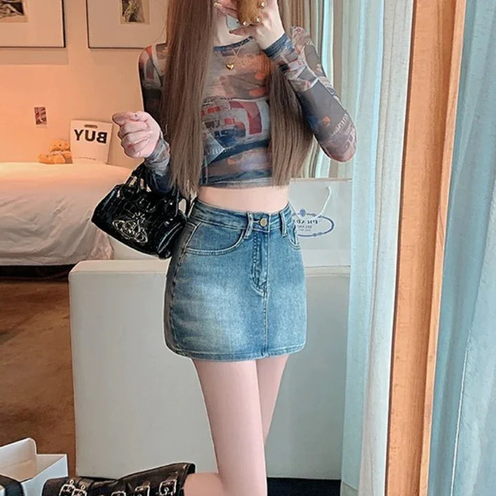Woman wearing a printed sheer long-sleeve crop top and denim mini skirt holding a black handbag indoors