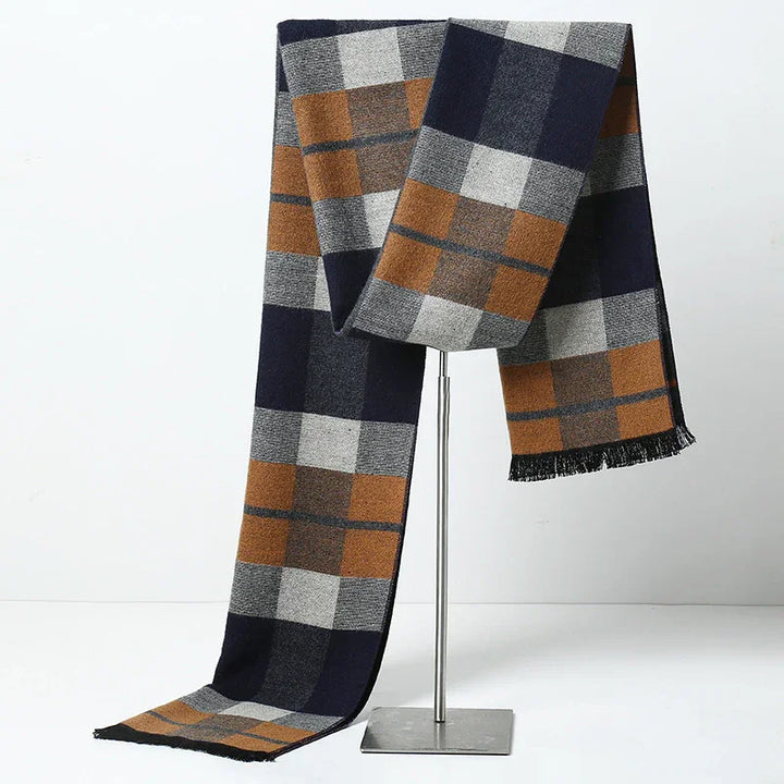 Plaid wool scarf in brown, navy, gray, and black displayed on metal stand on white background