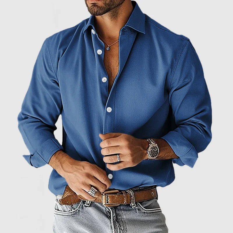 Man wearing blue button-down shirt with rolled sleeves, brown leather belt, and silver watch