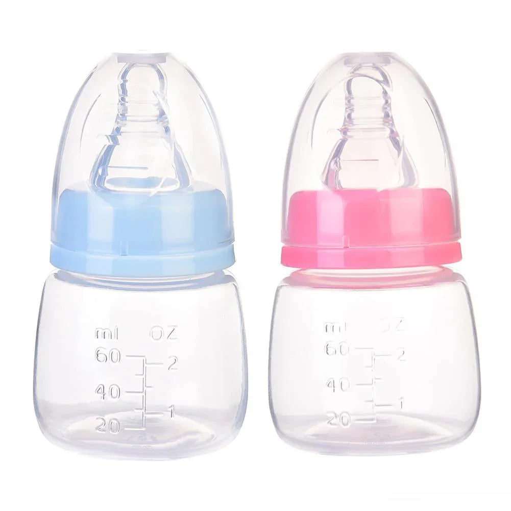 Two small baby bottles with clear bodies and measurement markings, one with a blue cap and one with a pink cap