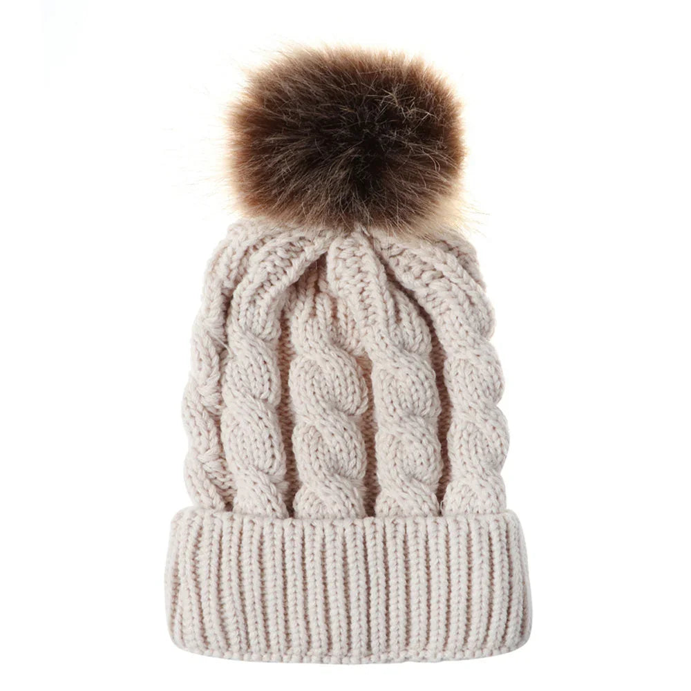 Beige cable knit winter beanie with folded cuff and brown faux fur pom pom