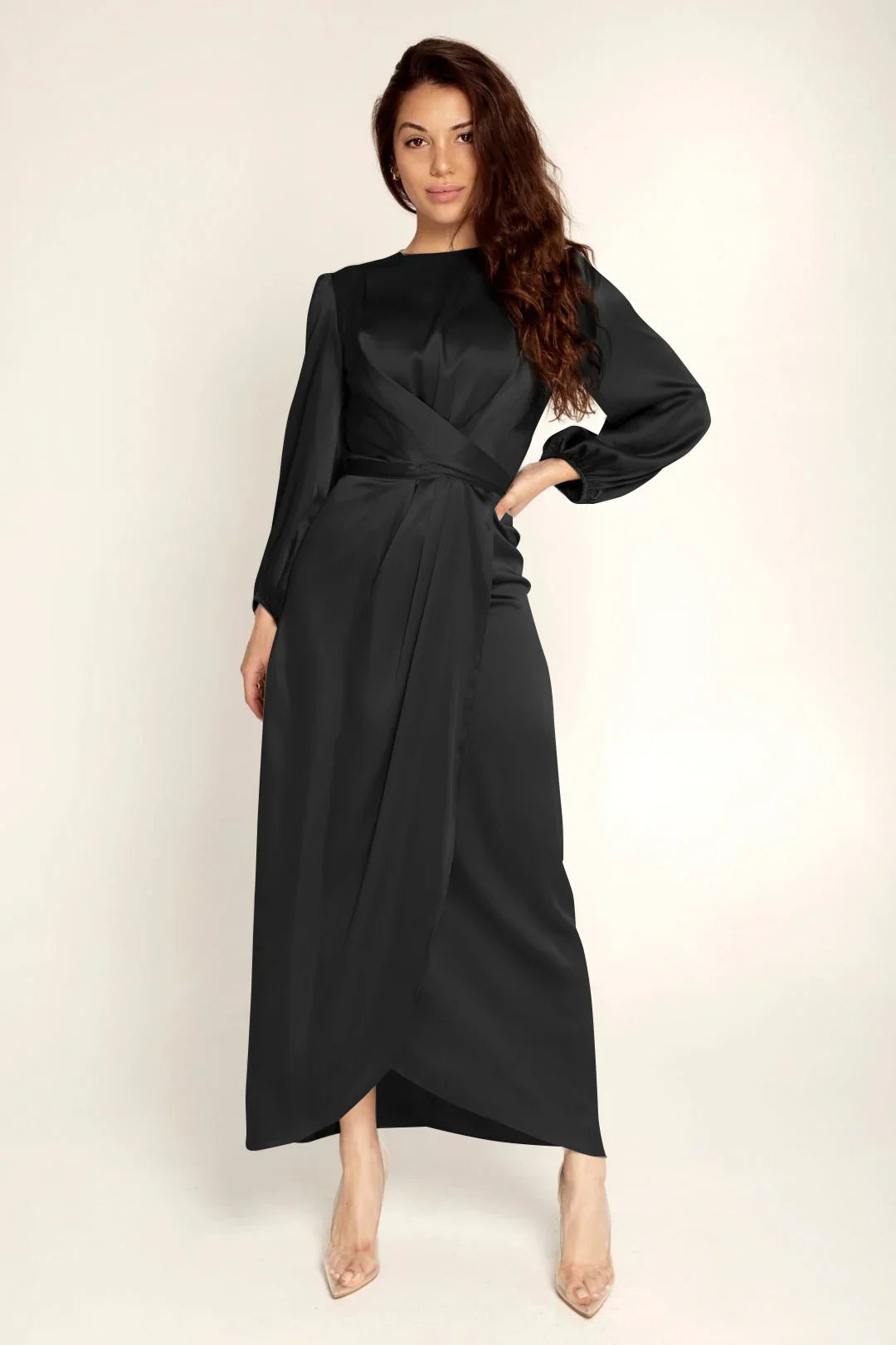 Woman wearing elegant long black satin dress with long sleeves and wrap design