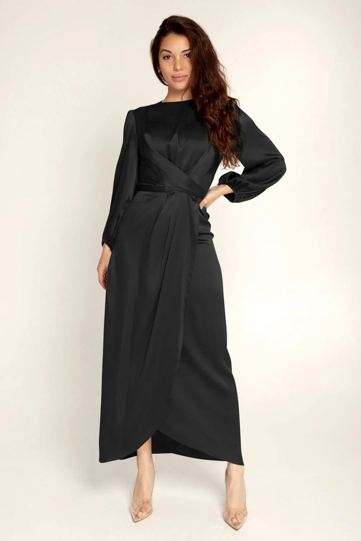 Woman wearing elegant long black satin dress with long sleeves and wrap design