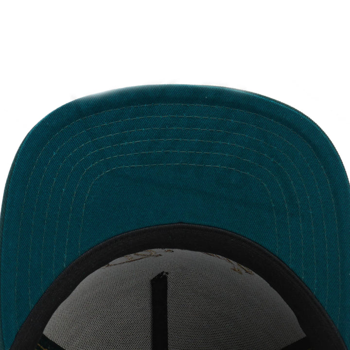 Close-up of teal green fabric cap brim with black inner band and white mesh lining
