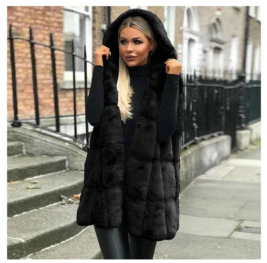 Woman wearing black faux fur hooded vest and black turtleneck in urban street setting