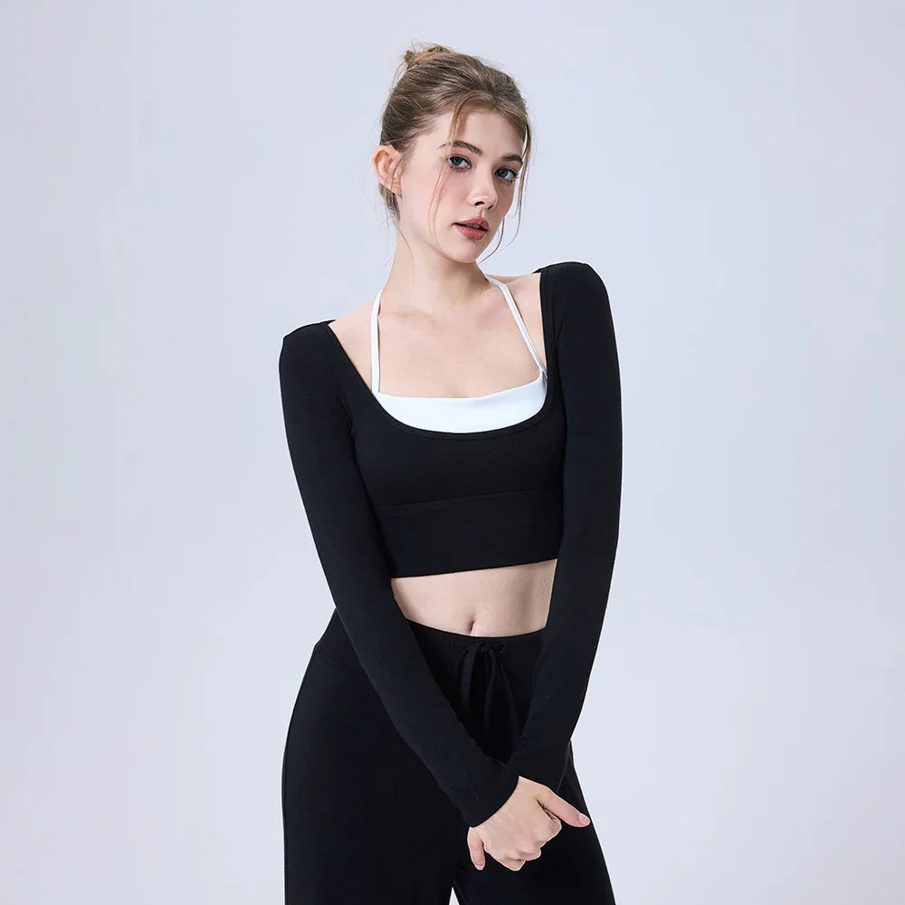 Young woman wearing black long sleeve crop top and black pants on plain background