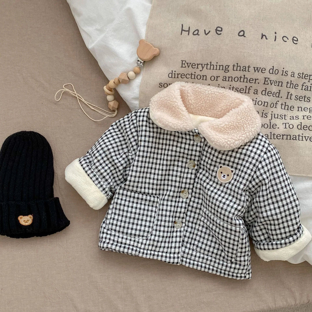 Baby checkered jacket with sherpa collar and bear patch, black knit hat with bear emblem, wooden pacifier clip