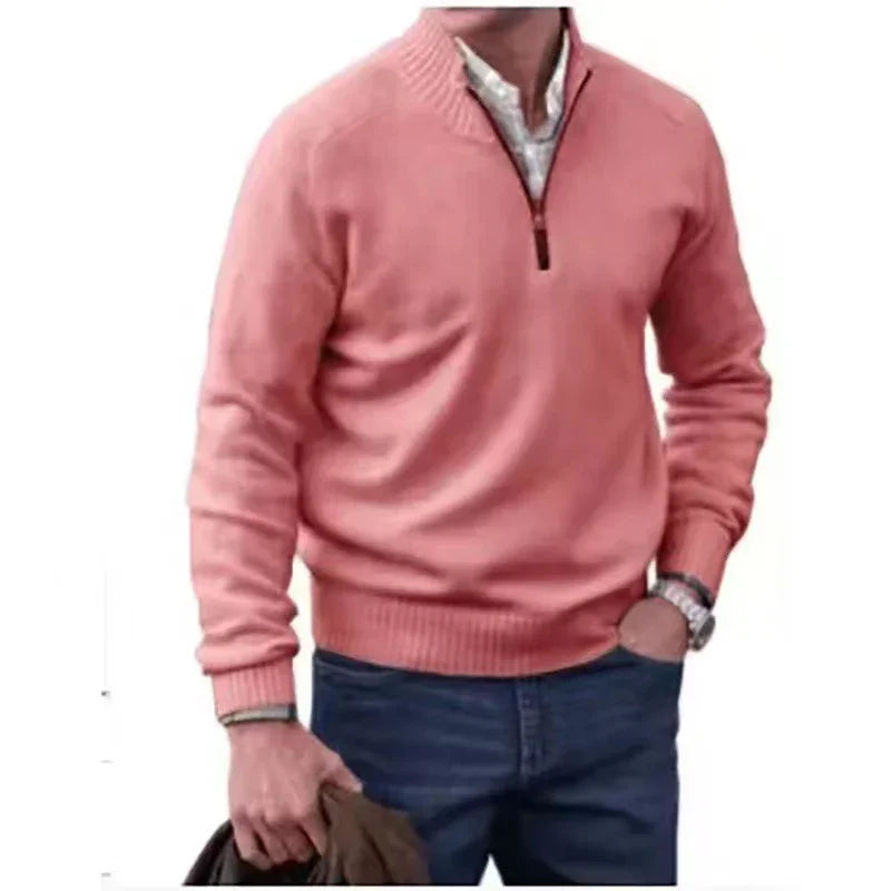 Man wearing pink quarter-zip sweater over white shirt with blue jeans, holding jacket in hand