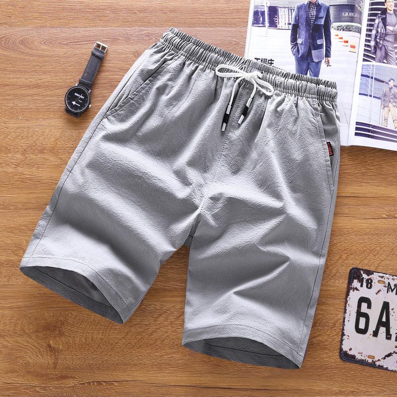 light gray casual men's shorts with elastic waistband and white drawstring on wooden surface