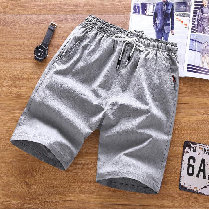 light gray casual men's shorts with elastic waistband and white drawstring on wooden surface