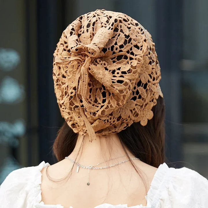 Back view of woman wearing brown floral lace crochet hat with bow detail and white ruffled top