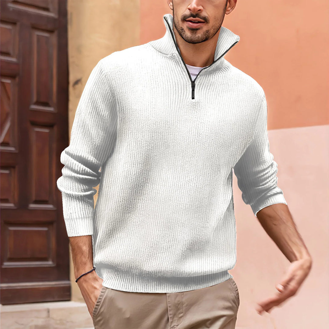 Man wearing white half-zip ribbed sweater with beige pants in urban outdoor setting