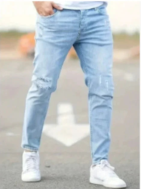 Person wearing light blue distressed skinny jeans and white sneakers standing outdoors on pavement