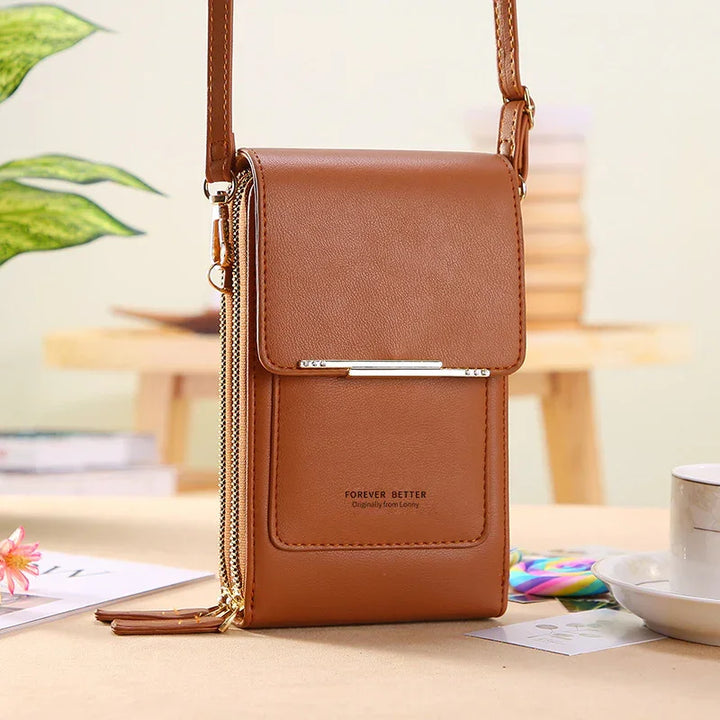 Brown leather crossbody bag with gold zippers and strap, stylish compact design on table