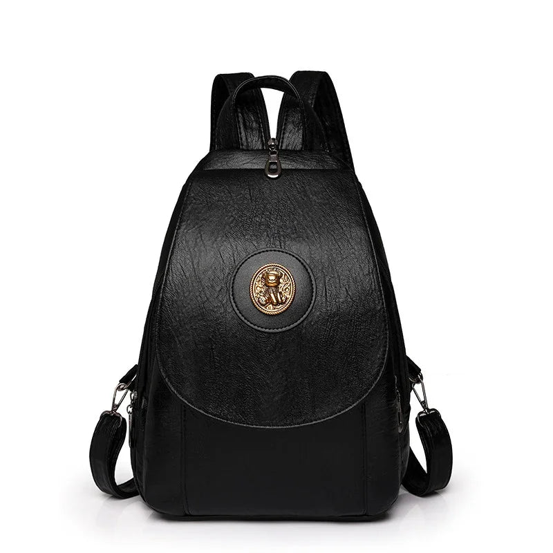 Black leather backpack with a gold medallion featuring a lion design on the front flap