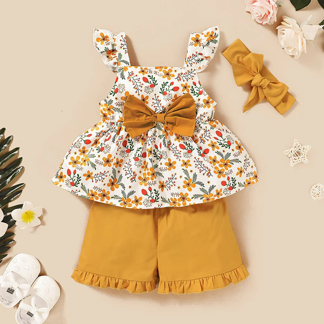 Baby girl floral print top with mustard bow, matching mustard shorts with ruffles, and bow headband set