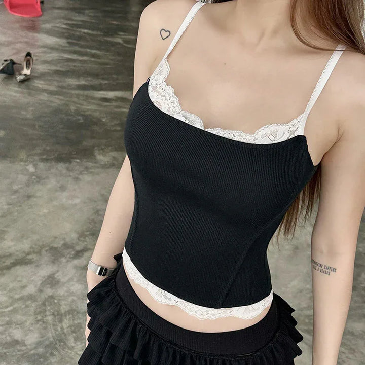 woman wearing black ribbed camisole with white lace trim and black ruffled skirt on concrete floor