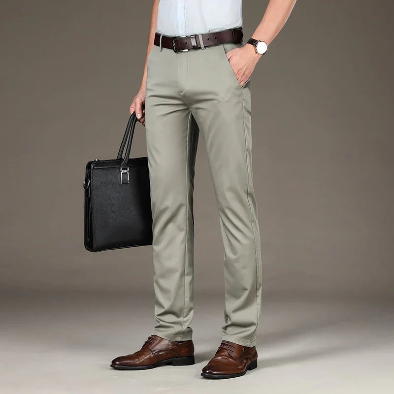Man wearing light gray formal pants, brown leather belt and shoes, holding black briefcase
