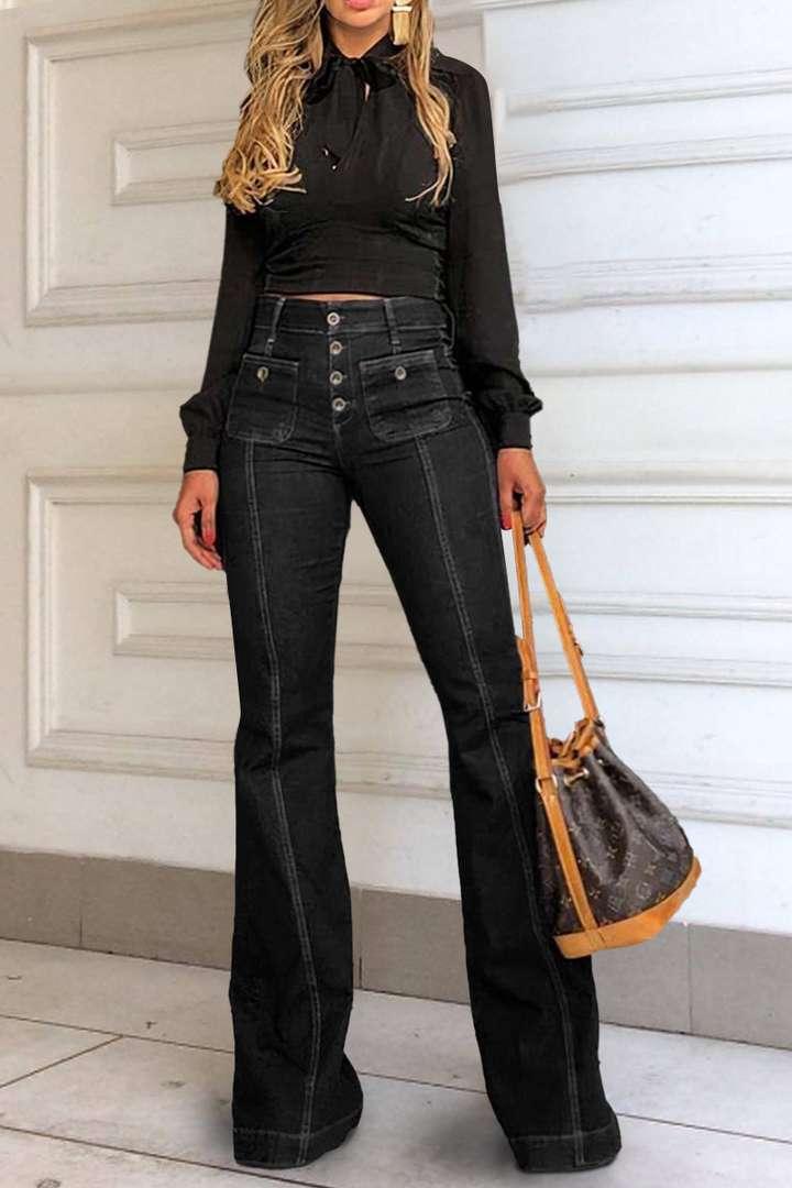 Woman wearing black high-waisted button-up flare jeans and long-sleeve black top holding brown designer handbag
