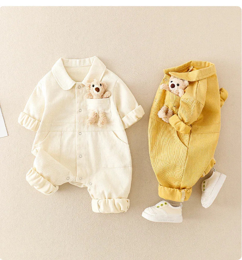 Two baby rompers in cream and mustard yellow with teddy bears in breast pockets and white baby shoes
