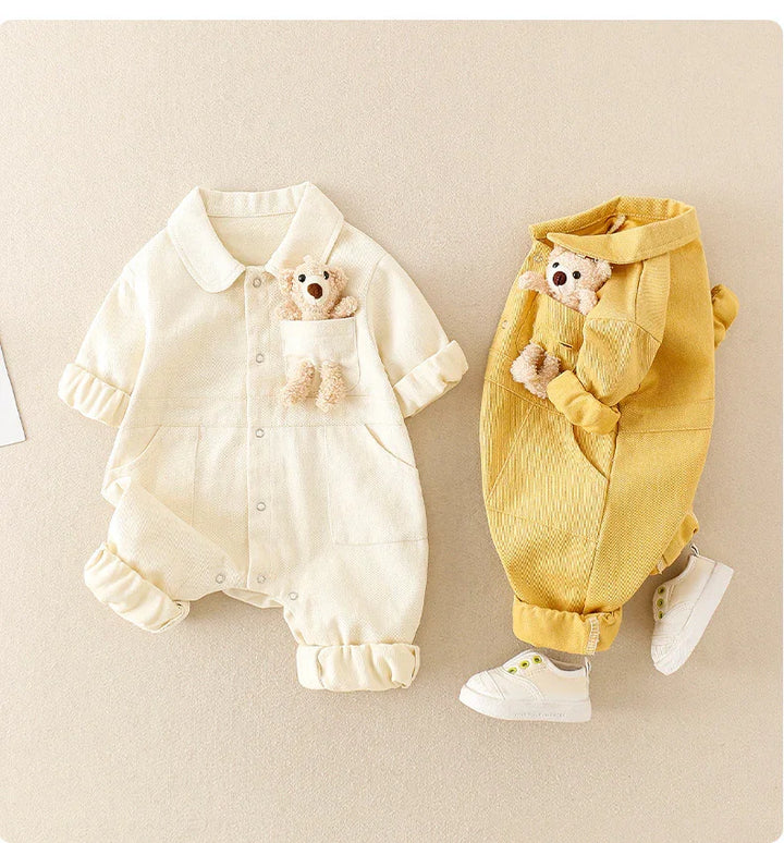 Two baby rompers in cream and mustard yellow with teddy bears in breast pockets and white baby shoes