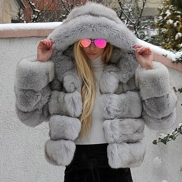 Woman wearing a luxurious gray fur hooded jacket and pink reflective sunglasses in a snowy outdoor setting