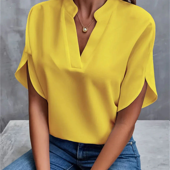 Woman wearing bright yellow short-sleeve blouse with V-neck and casual blue jeans