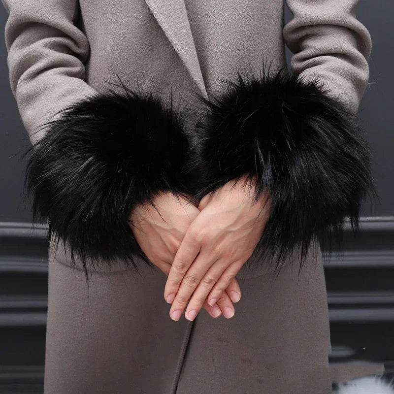 Person wearing gray coat with black fluffy fur cuffs on sleeve ends, hands clasped in front