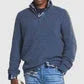 Man wearing a navy blue quarter-zip pullover sweater and light blue jeans against white background