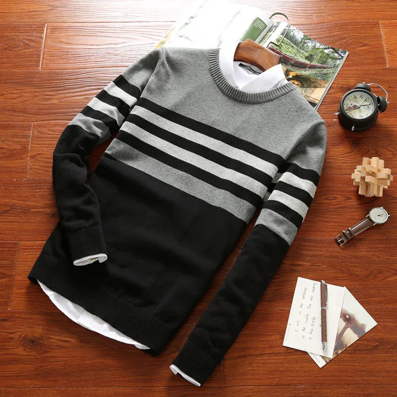 Men's crew neck knitted sweater with black and gray stripes laid flat on wooden floor with watch and clock