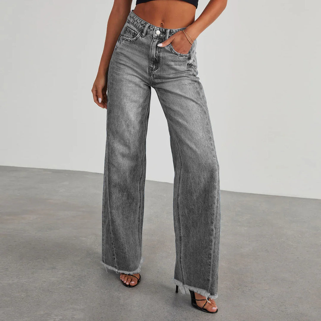 Woman wearing high waisted black wide leg jeans with frayed hems and black strappy heels