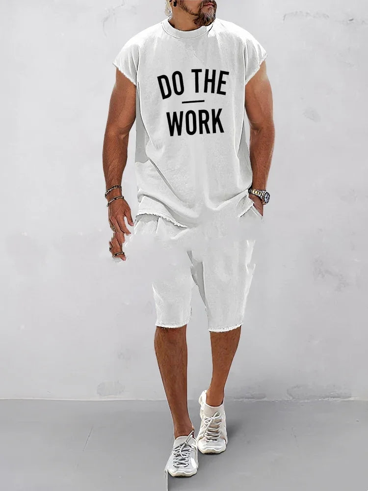 Man wearing white sleeveless shirt with Do The Work text and white shorts walking indoors