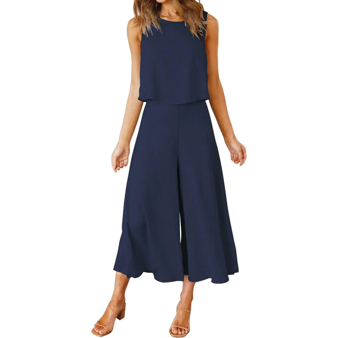 Woman wearing navy blue sleeveless wide-leg jumpsuit with cropped top and sandals