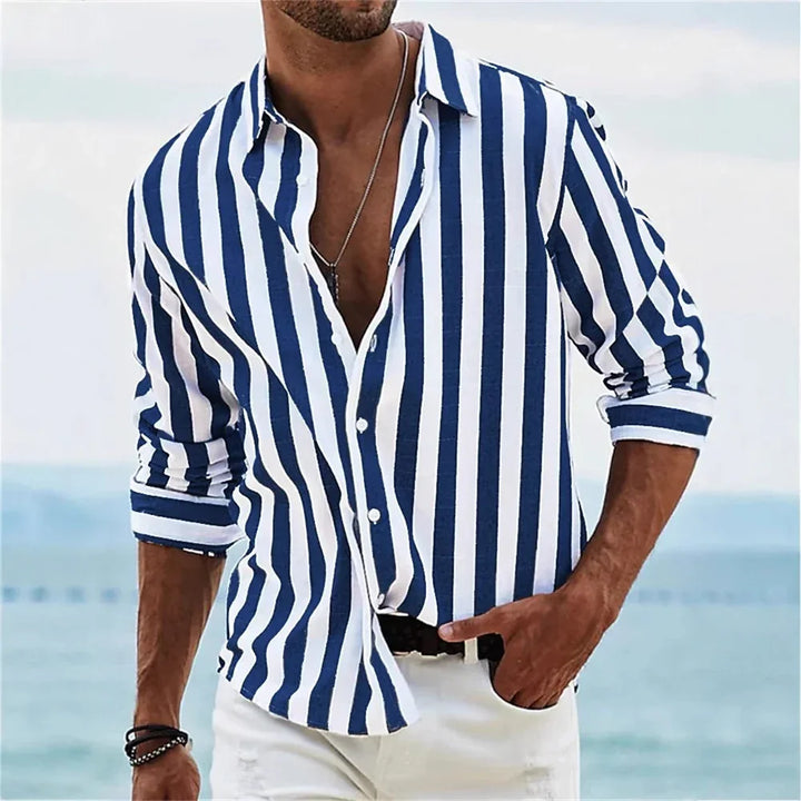 Man wearing blue and white vertical striped casual shirt with rolled sleeves by the beach