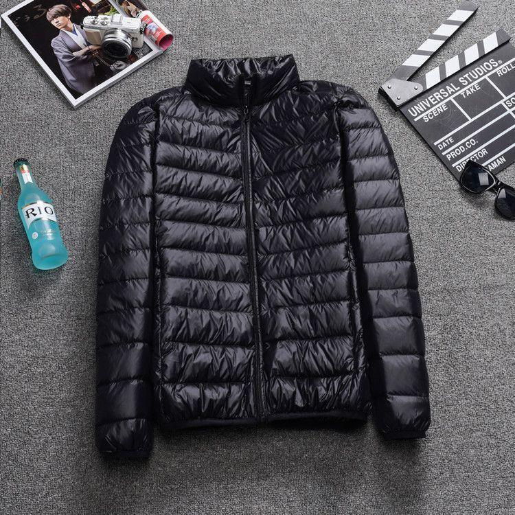 Black lightweight puffer jacket with zipper on gray carpet next to sunglasses, clapperboard, magazine, and blue RIO bottle