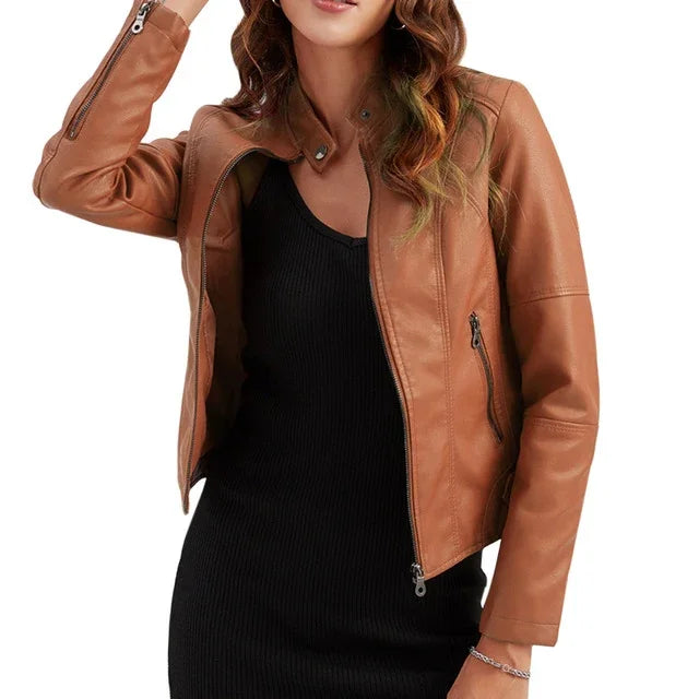 woman wearing stylish brown leather jacket over black ribbed dress, posing with hand on head