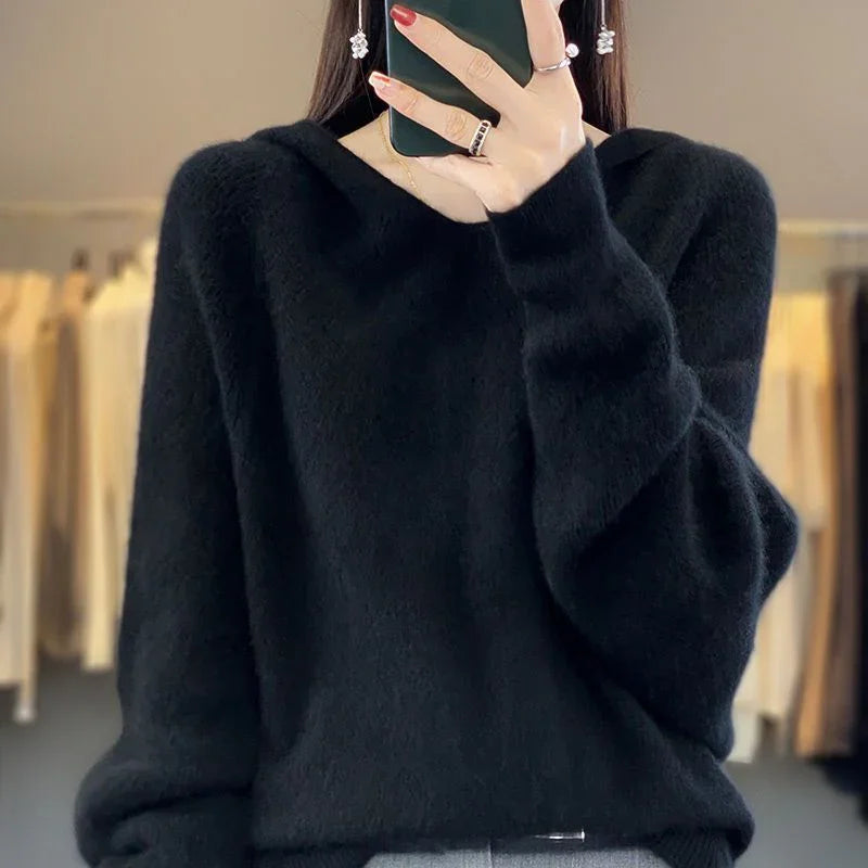 Woman wearing black fuzzy sweater and silver earrings taking mirror selfie indoors