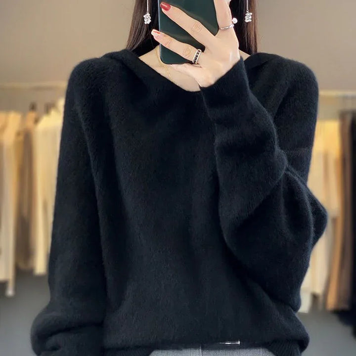 Woman wearing black fuzzy sweater and silver earrings taking mirror selfie indoors