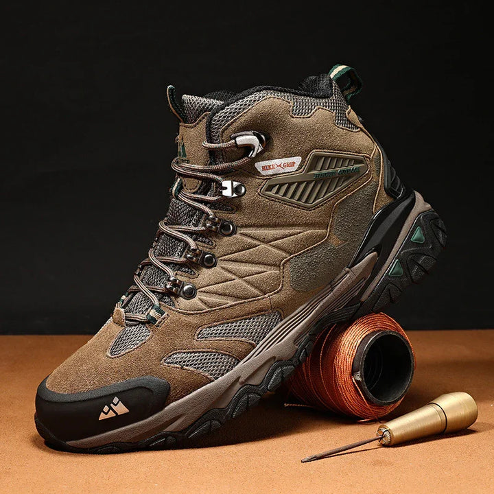 Brown and black hiking boot with rugged sole and lace-up design, displayed on brown surface with spool and tool