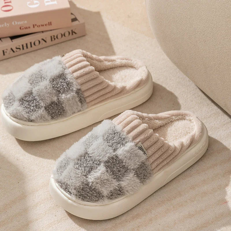 Cozy fuzzy slippers with grey and white checkerboard pattern and ribbed beige collar on beige carpet